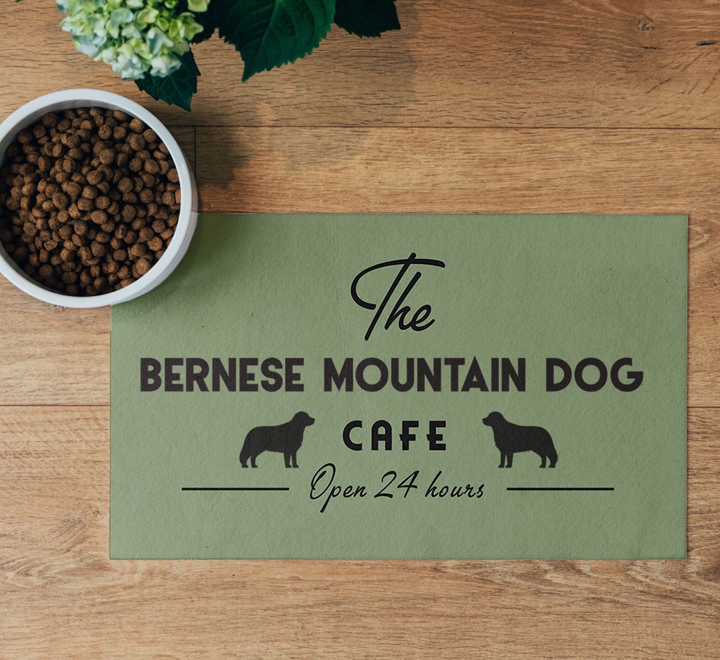 'The {breedFullName} Cafe' Feeding Mat - flatlay on wooden floor with bowl