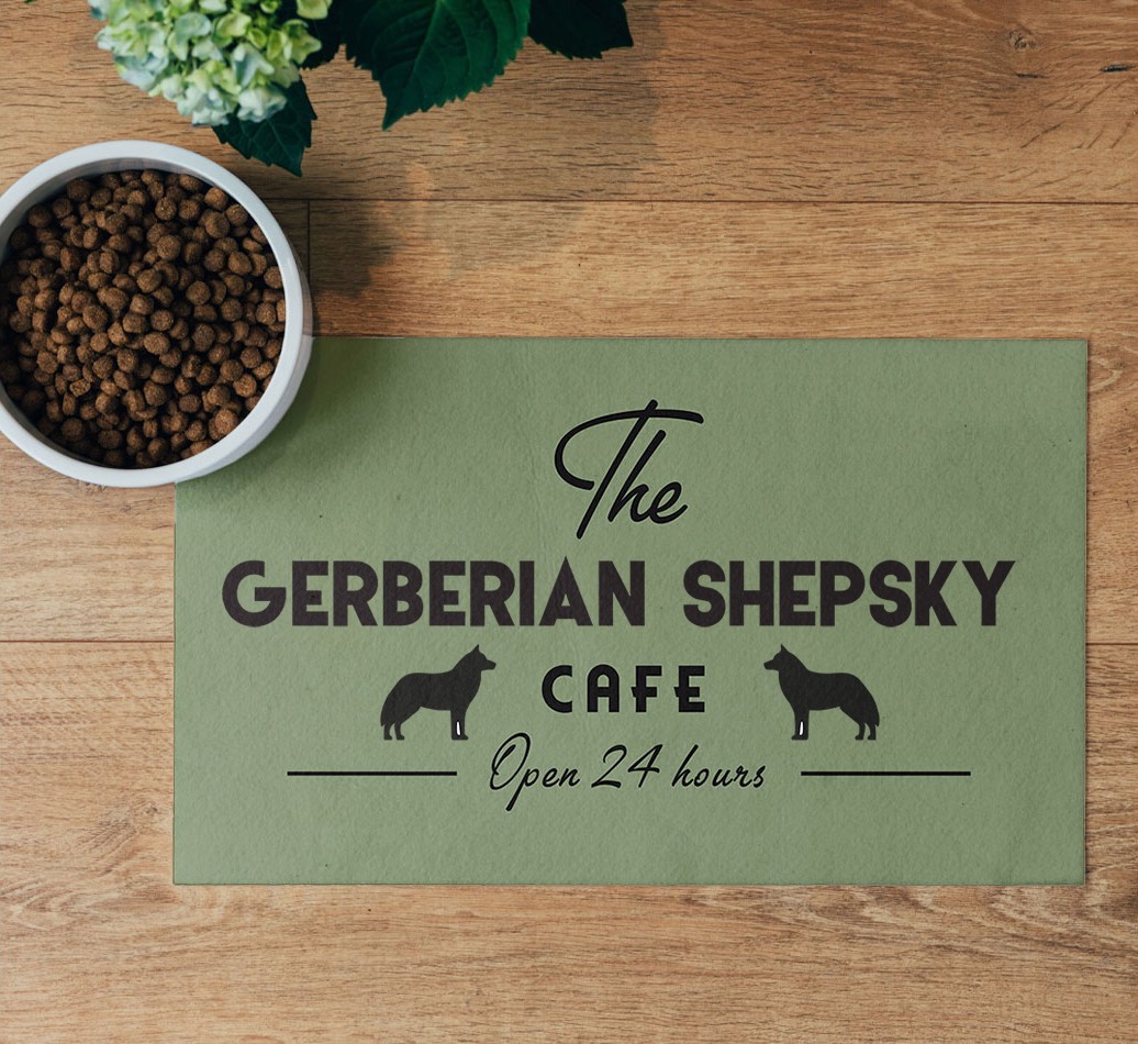 'The {breedFullName} Cafe' Feeding Mat - flatlay on wooden floor with bowl