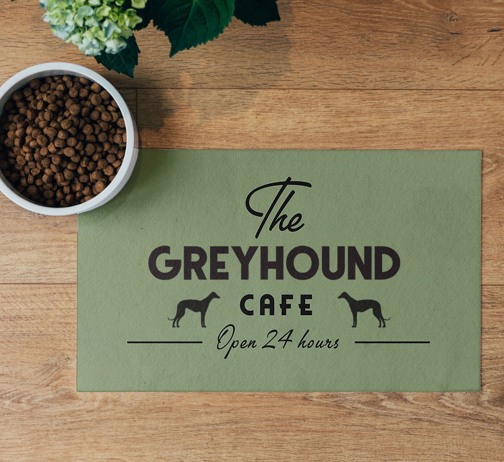 'The {breedFullName} Cafe' Feeding Mat - flatlay on wooden floor with bowl