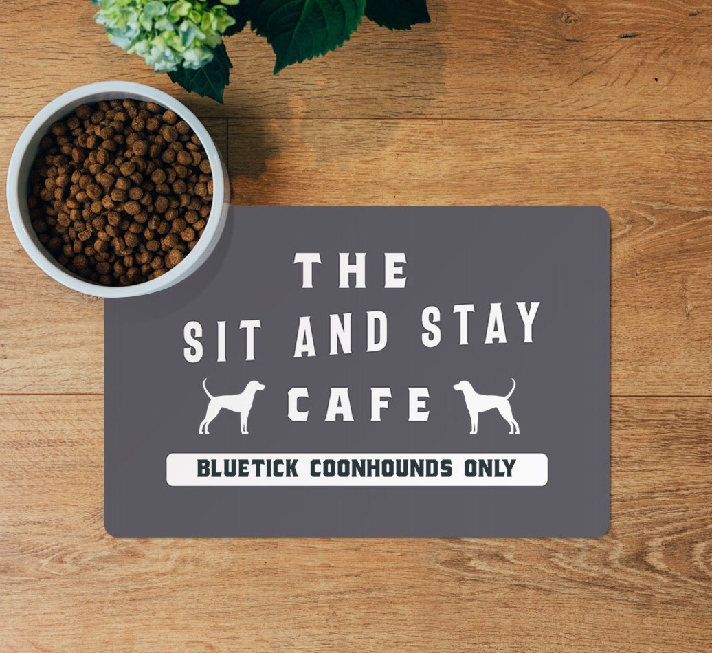 Sit and Stay Cafe: Personalized {breedFullName} Feeding Mat - layed flat on wooden floor with bowl