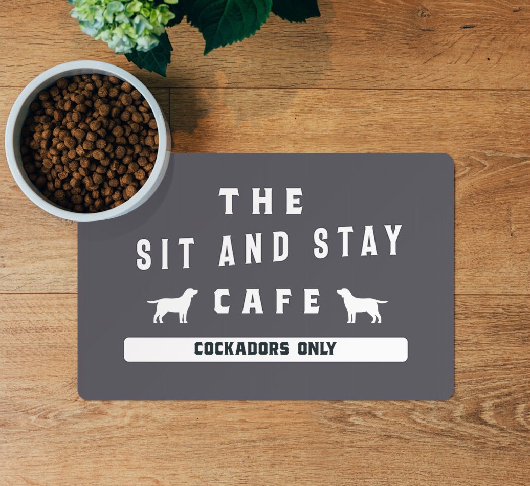 Sit and Stay Cafe: Personalized {breedFullName} Feeding Mat - layed flat on wooden floor with bowl