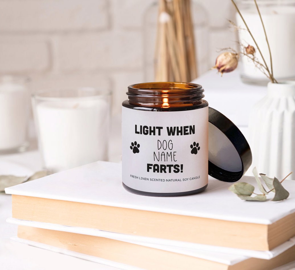Light To Cover Farts: Personalised Candle - on books on a bedside table